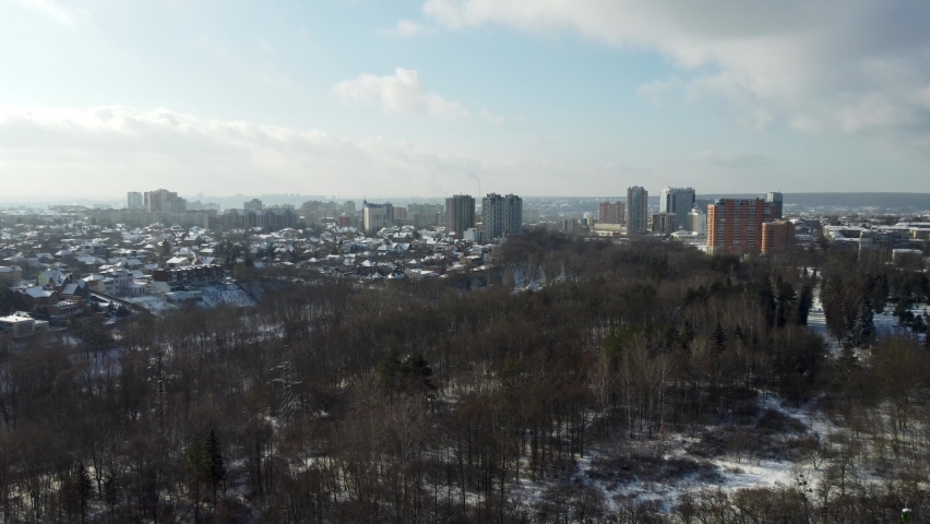 Aerial right to left panorama of Kharkiv city center with Park of Maxim Gorky, Sokolniki, stadium and residential multistorey buildings with scenic bright cloudy sky in winter Royalty-Free Stock Footage #1077329159
