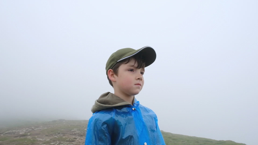 Travel to the mountains with his son in summer. Summer hiking in the Alps. The boy went to the top of the mountain in the clouds.