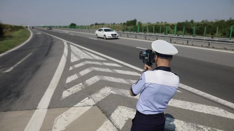 Bucharest, Romania - August 10, 2021: Romanian road police officer using a mobile radar on the highway.