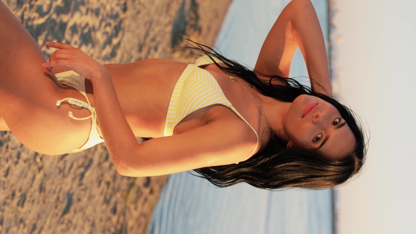 people, summer and swimwear concept - happy smiling young woman in bikini swimsuit posing on beach