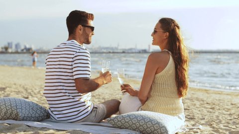 leisure, relationships and people concept - happy couple drinking champagne on summer beach