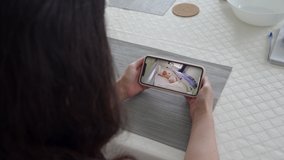 Mother using ip wireless security camera as baby video monitor on mobile phone, woman watching her sleeping baby in real-time. High quality 4k footage