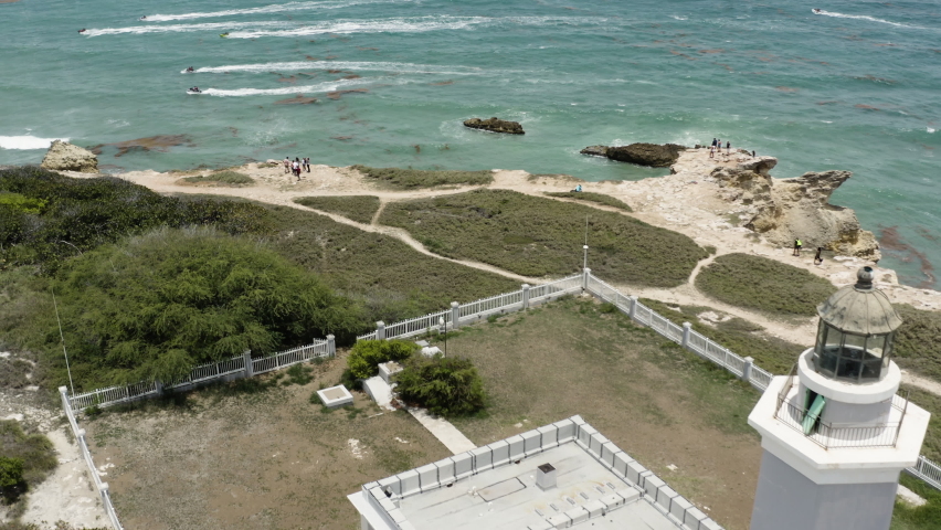 Aerial pull out reveal of Faro Morrillos Cabo Rojo Lighthouse on top of limestone cliffs in Puerto Rico.