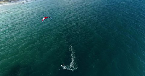 Red and white kite. Athlet ride on the board makes a turn.  Drone fly around kitesurfer.
Drone footage of kiter riding at sunset. The ocean has clear blue water.A kite surfers rides in ocean lagoon