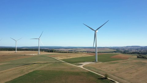 A road joins the wind turbines dominating the Nivernais countryside, its wheat fields after the harvest and the green forests in Oisy, towards Clamecy, in the Nièvre, in Burgundy, in France, in summer