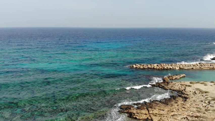 4k Coastline of Cyprus and azure sea with waves. Motion of the camera.