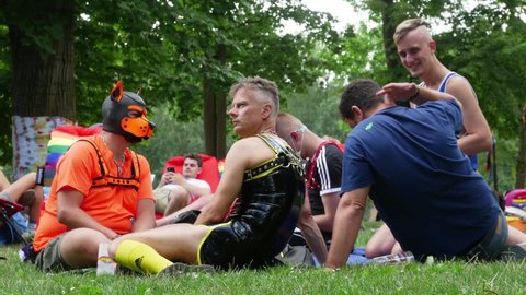 Group BDSM clothes people talking. They discussing something LGBTQ+, gesticulating. Transmission oral message. Leisure activities in city park. Creative expression. CZ, Prague, Strelecky, 4.8.2021. 