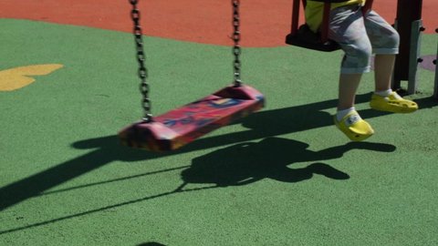 Swing and child, full and empty swing in the playground, sunlight and shadow
