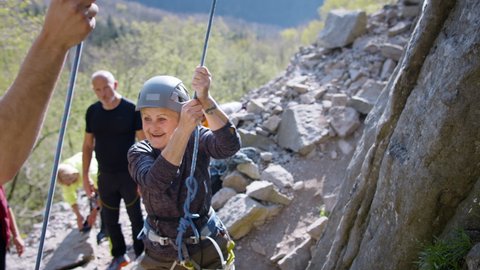Group of seniors with instructor celebrating successful rocks climbing outdoors in nature, active lifestyle. Video Stok