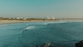 Baleal, Portugal, Europe. Picturesque coastal town washed with bluish sea waters as seen from above. Drone footage of the surfers catching a wave. High quality 4k footage