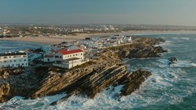 Baleal, Portugal, Europe. Aerial footage of rocky formation with waterscape in the background. Beautiful coastal village with residential cottages within the sea. High quality 4k footage