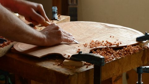 Luthier working with a gouge manufacturing a new instrument