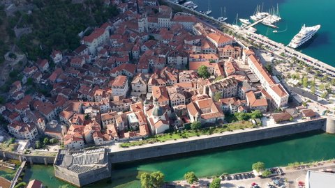 Old town Kotor Montenegro on the coast of Boka bay in the Mediterranean. Vacation destination and tourist trap in Europe. Aerial drone view of waterfront and stone houses on a sunny summer day.