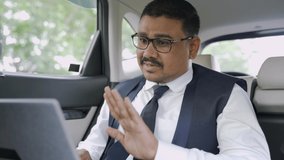 Businessman on video call or attending metting in laptop while travelling in car - concept of successful business, modern lifestyle, internet, technology and communication.