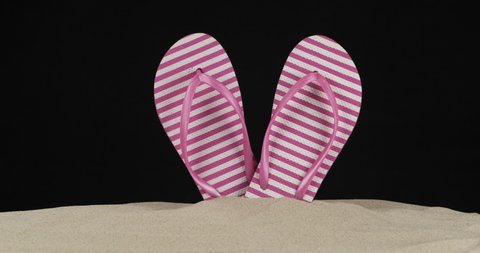 Panorama of beachside flip-flops sticking out of the sand. Isolated. Black background