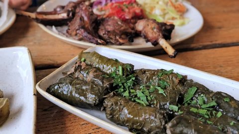Stuffed Greek Wine Grape Leaves (dolmades) with Roasted Lamb Chops Ribs with spices, vegetables. Selective focus