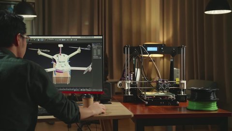 Back View Of Asian Engineer Thinking While Work On Personal Computer And 3D Printer, Screen Shows Cad Software With 3D Prototype Of Drone Delivery
