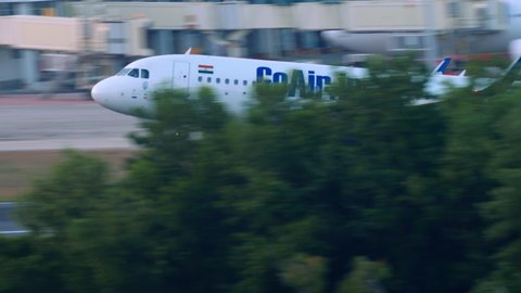 PHUKET, THAILAND - DECEMBER 1, 2018: GoAir Airbus 320 VT-WGQ landing at Phuket International Airport. The moment of touching the runway. Plane landing on an island with palm trees