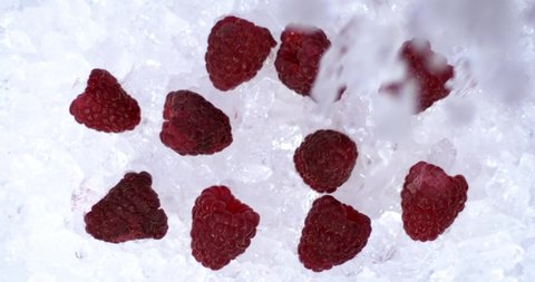 Cold ice falls on raspberries in ice on a white background, cold fruits for fresh juice, cold tea or yogurt. Natural vitamin fruit. Red fresh raspberry cold. Filmed on high speed camera. 4K.