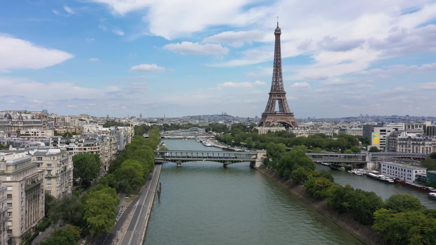 France, Paris Tour Eiffel (Eiffel Tower), cloudy summer day, with Pont d'Iena and Bir-Hakeim Bridge. Long drone shot, aerial view along the Seine river. Royalty-Free Stock Footage #1077409007