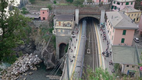 Riomaggiore, Italy - June 11. 2021: Train Station in Cinque Terre, Train entering station and different train departing Riomaggiore Train Station. Trenitalia Passenger line Aerial view