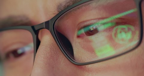 Close Up eyes of a asian man looking at laptop in evening - The light from monitor is reflected on his glasses with ransomware web