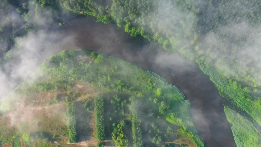 Drone aerial shot of natural river covered with morning fog