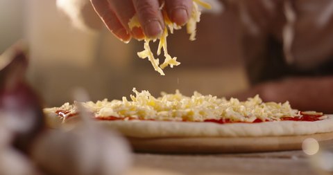 Close up shot of chef putting shredded cheese on pizza dough with tomato sauce. Process of making traditional italian handmade pizza 4k footage