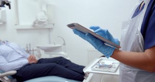 Close up caucasian female nurse typing on digital tablet while waiting for patient 