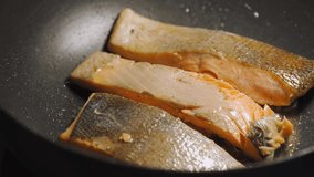 Fried salmon with butter on a black pan. Loop. seamless clip. Healthy menu with low calories.