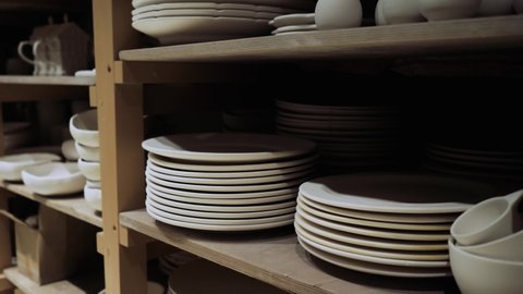White ceramic plates are on the shelves in the production shop and waiting for painting. Sale of white ceramic plates without final coating. High quality 4k footage