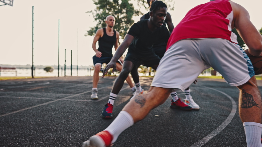 Basketball team practice at sunrise. Friendly match on the basketball field, multiracial group of athletes. Royalty-Free Stock Footage #1077437300