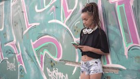 Young modern woman uses a smartphone against a wall with street graffiti. concept of modern urban youth - Powered by Shutterstock - Get 15% off with code: PIKWIZARD15