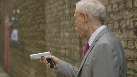 LONDON - NOVEMBER 3, 2012: A criminal pointing a gun in an alley