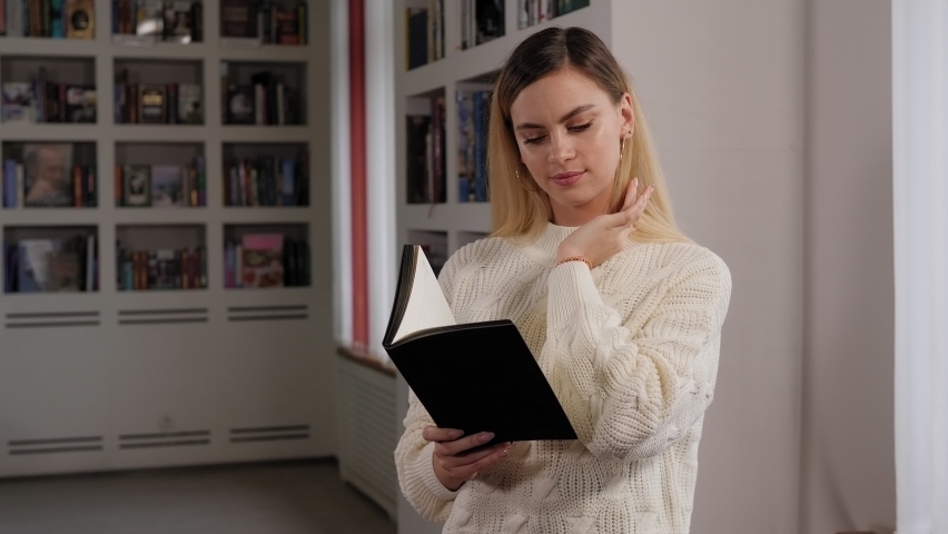 Portrait of a student girl with a book in her hands in the library.