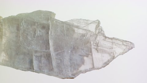 Raw material for the production of gypsum, plaster and drywall. Renovation, construction, Drywall. Large transparent crystal on a background. Gypsum Rubrum or Gypsum Fibrosum. Vertical footage. 