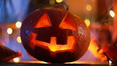 Halloween pumpkin head illuminated from inside, bokeh lights on background. Carved pumpkin Jack o lantern Halloween home decor.