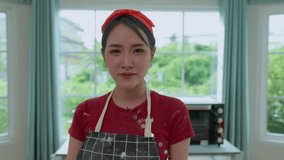 Slow moving. Happy beautiful Asian woman with kitchen apron making bread at home . Shooting live Vlog videos. Hobby, leisure activities, homemade, bake cookies and cakes summer holiday. Streaming.