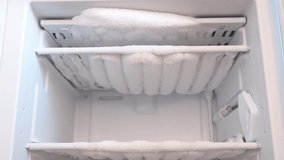 Close-up of opened deep freezer with ice and snow. Freezer before defrost. Empty shelves of fridge. Video 4k resolution.