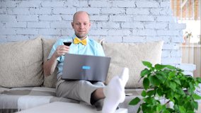 Virtual holiday. Elegant man in shirt and bow tie with glass of wine on online date via call. Happy man says toast and remotely celebrates holiday in video chat in self-isolation. Love in lockdown.