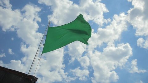 Low angle of a green flag on the beach waving in slow motion.
