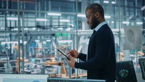 Car Factory Office: Portrait of Successful Black Male Chief Engineer Using Tablet Computer in Automated Robot Arm Assembly Line Manufacturing High-Tech Electric Vehicles. Medium Side View - Powered by Shutterstock - Get 15% off with code: PIKWIZARD15