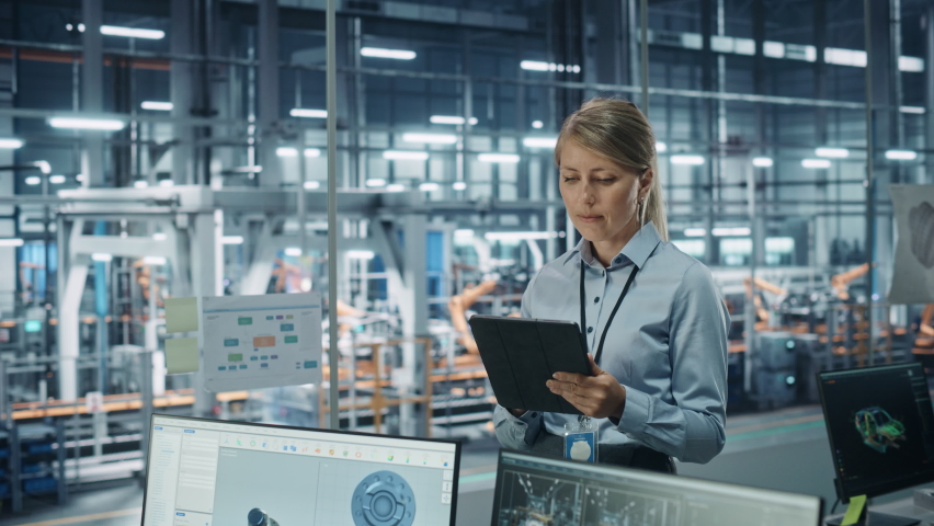 Car Factory Office Concept: Portrait of Successful Female Chief Automotive Engineer Using Tablet Computer to Design and Optimize Automated Robot Arm Assembly Line Manufacturing Electric Vehicles | Shutterstock HD Video #1077501974