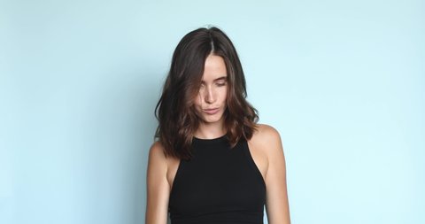 Urban subculture concept. Stylish cheeky woman wears trendy black top poses against blue wall has cheeky expression. Female posing, grimacing and have fun. 