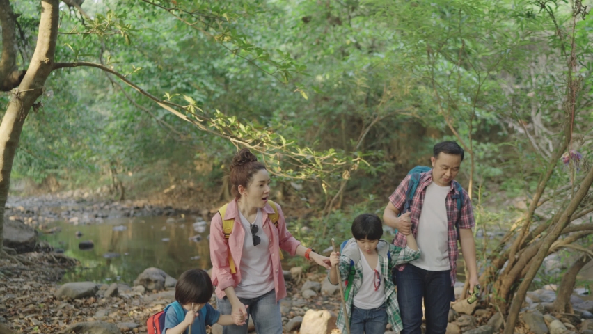 Asian family father and mother parents sash backpack two childhood sons Teach his son to walk, study, learn about nature. in the forest park during the holidays Royalty-Free Stock Footage #1077505802