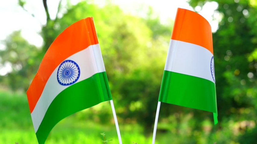 Two Indian tricolor national flags in nature background. Independence Day and Republic Day of India. 15 August Indian Tiranga crossed close-up view, Fan and national pride concepts