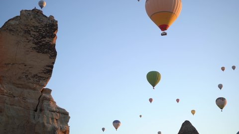 Goreme, Cappadocia, Turkey - May 30, 2021: Ballooning in Kapadokya. Video time lapse of many hot air balloons flying over unusual city streets, valleys and rocks in blue sunrise morning sky