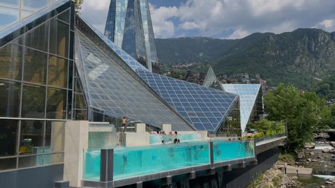 La Vella, Andorra, July 2021-People in the outdoor transparent wimming pool Caldea spa building in Andorra La Vella