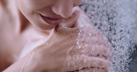 slow motion of a woman taking a shower, beautiful girl washing and enjoy herself under a shower, close up of hands and shoulder