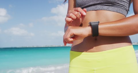 Smart watch woman using smartwatch touching button and touchscreen on active sports activity or morning run. Closeup of hands and wrist with smart watch screen